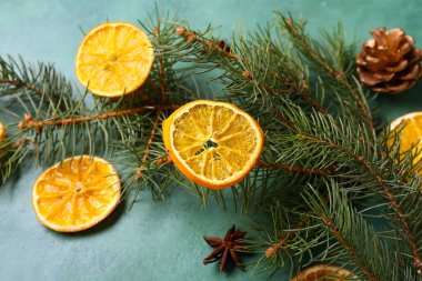 Köknar dallı kurutulmuş portakal dilimleri, yeşil arka planda yıldız anason ve çam kozalağı.