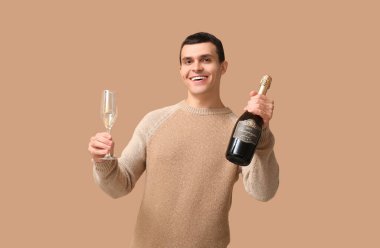 Elinde şişe ve bir bardak şampanyayla genç adam Noel 'i kahverengi arka planda kutluyor.