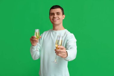 Şampanya kadehli genç adam Noel 'i yeşil arka planda kutluyor.