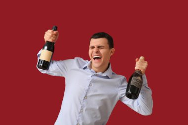 Şampanyalı mutlu genç adam kırmızı arka planda Noel 'i kutluyor.