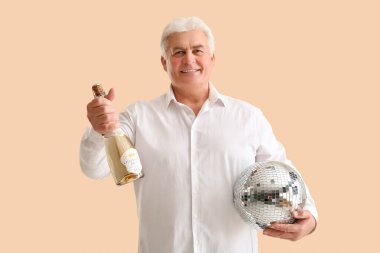 Bir şişe şampanyası ve disko topuyla son sınıf öğrencisi bej arka planda Noel 'i kutluyor.