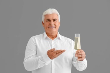 Bir bardak şampanyayla yaşlı adam gri arka planda Noel 'i kutluyor.