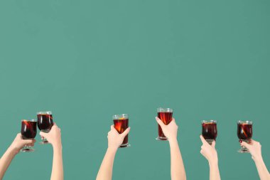 Yeşil arka planda sıcak şarap kadehleriyle kadın elleri.