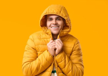 Sarı arka planda şık kabarık ceketli genç adam.