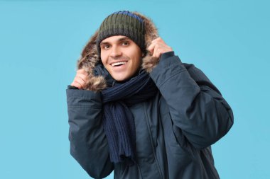 Şık kabarık ceketli genç adam ve mavi arka planda eşarp.