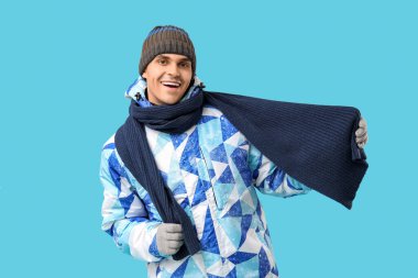 Şık kabarık ceketli genç adam ve mavi arka planda eşarp.