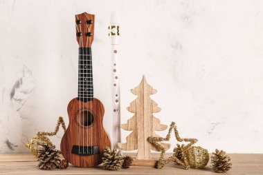 Ukulele, flüt ve Noel süslemeleri ile ahşap masa üzerinde hafif arka planda kompozisyon