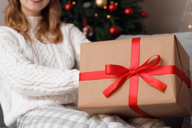 Evde Noel hediyesi kutusu olan genç bir kadın, yakın plan.