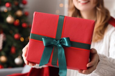 Evde Noel hediyesi kutusu olan genç bir kadın, yakın plan.