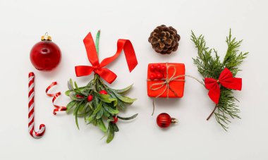 Beyaz arka planda Noel süslemeleri olan ökseotu dalı