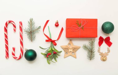 Beyaz arka planda Noel süslemeleri olan ökseotu dalı