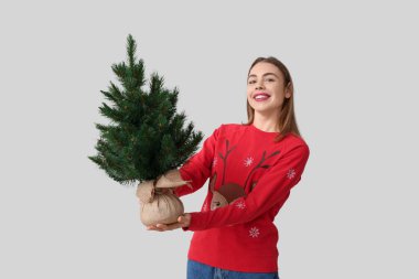 Beyaz arka planda Noel ağacı olan mutlu genç bir kadın.