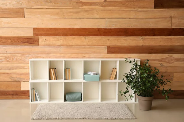 TV stand with books and plant near wooden wall in room