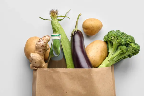 Paper shopping bag with fresh vegetables on grey background