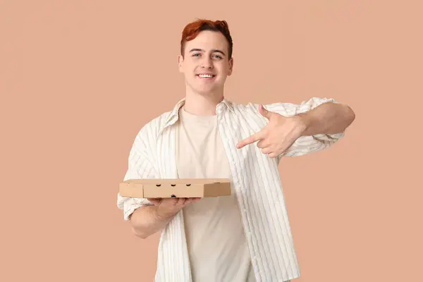 Junger Mann Zeigt Auf Karton Mit Leckerer Pizza Auf Braunem — Stockfoto