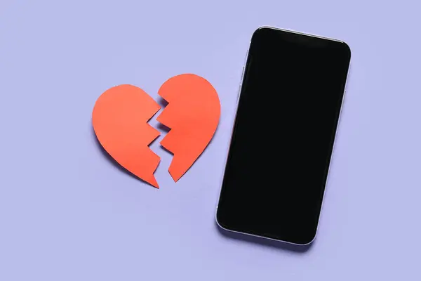 Modern mobile phone and broken paper heart on color background. Valentines Day