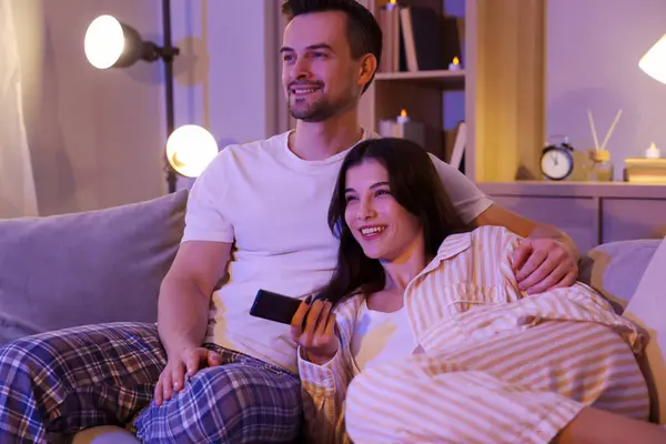 Young couple watching TV at home in evening