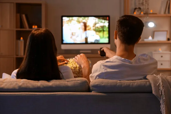 Couple with popcorn watching TV at home in evening