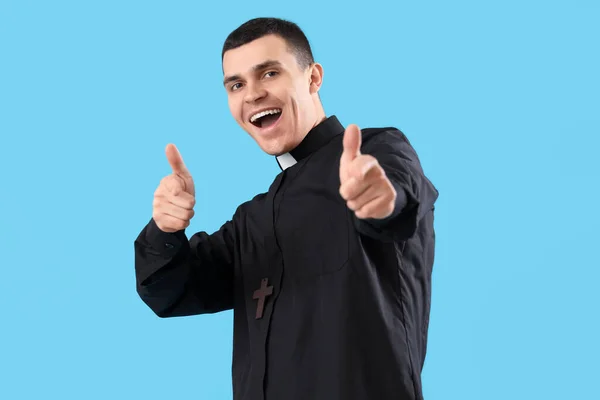 青い背景に親指を示す若い司祭 — ストック写真