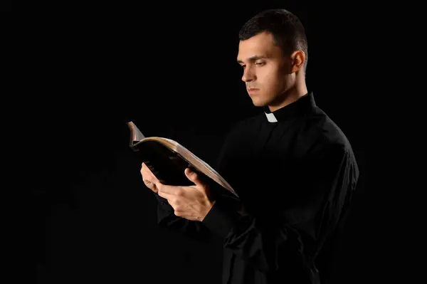 Young Priest Reading Holy Bible Dark Background — Stock Photo, Image