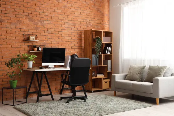 Interior of office with workplace, shelf unit and sofa