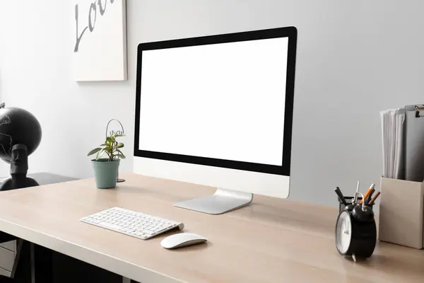 Blank computer monitor with alarm clock on table in office
