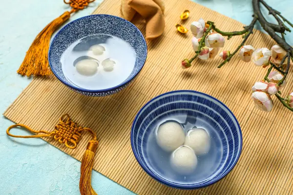 Bambu hasırı, tangyuan kâseleri, Çin dekoru ve mavi arka planda sakura. Dongzhi Festivali