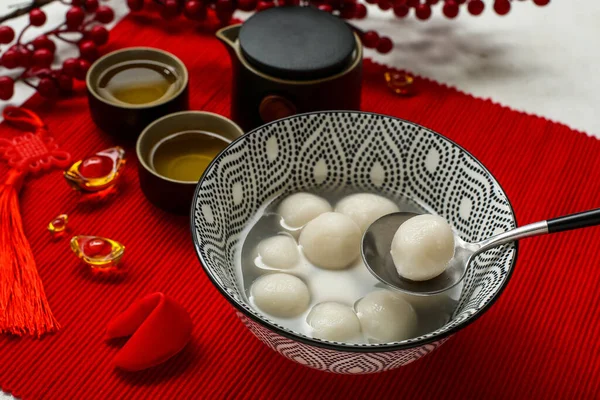 Bir kase tangyuan, çay ve Çin dekoru kırmızı hasırda, yakın plan. Dongzhi Festivali