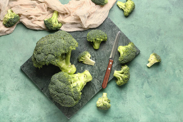 Board with fresh broccoli cabbages on green background