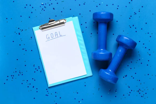 Paper sheet with text GOAL and dumbbells on blue background