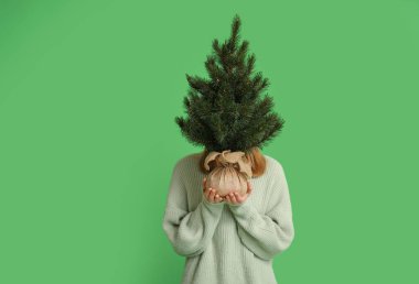 Yeşil arka planda Noel ağacı olan genç bir kadın.