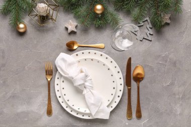 Noel ağacı dalları ve gri arka planda mumlar olan güzel bir masa.