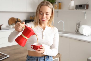 Modern mutfakta gayzer kahve makinesinden fincana espresso döken güzel bir kadın.