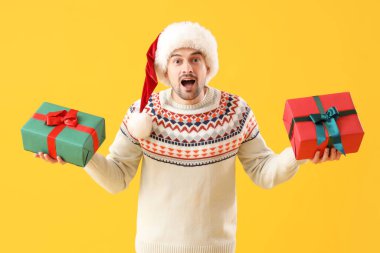 Sarı arka planda Noel Baba şapkalı şok olmuş bir adam.