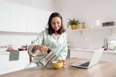 Modern mutfakta gayzer kahve makinesinden fincana espresso döken güzel bir kadın.