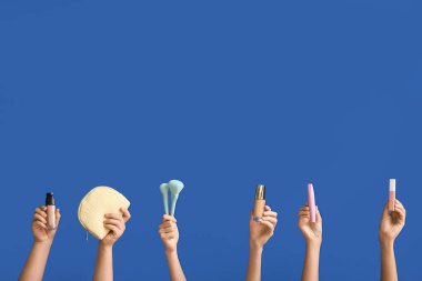 Renkli arka planda kozmetik ürünleri ve aksesuarları olan kadın elleri