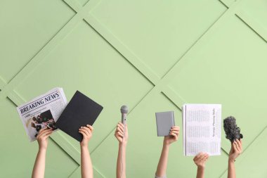 Renk duvarına karşı gazete, mikrofon ve defter tutan kadın elleri