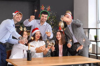İşyerinde yeni yılı kutlamak için maytaplı ve şampanyalı genç iş arkadaşları.