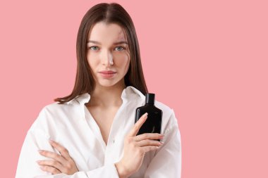 Pembe arka planda parfümü olan güzel bir genç kadın, yakın plan.