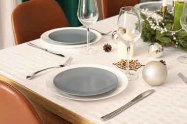 Temiz tabaklar, şarap bardakları ve Noel süslemeleri ile şenlik masası, yakın plan.