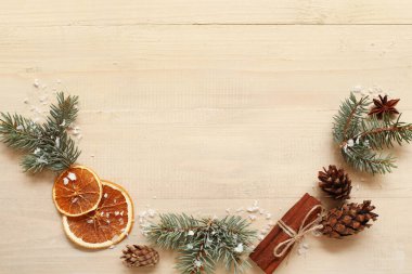 Açık ahşap zemin üzerinde kurumuş portakal, koni ve tarçın bulunan köknar dallarından yapılmış çerçeve. Kış gündönümü kavramı