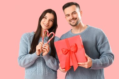 Noel hediyeli genç çift ve pembe arka planda şeker kamışı