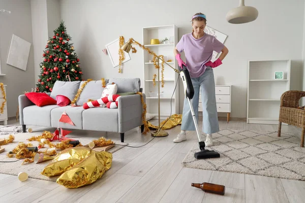 Female janitor cleaning carpet in messy living room after New Year party