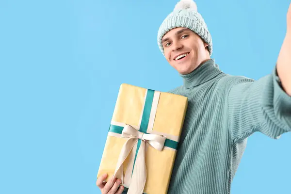 Feliz Joven Con Regalo Navidad Tomando Selfie Sobre Fondo Azul —  Fotos de Stock