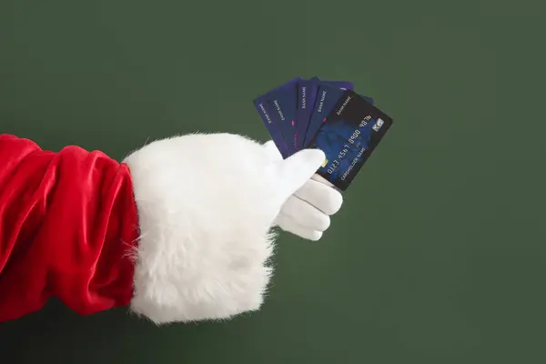 Santa hand with credit cards on green background, closeup