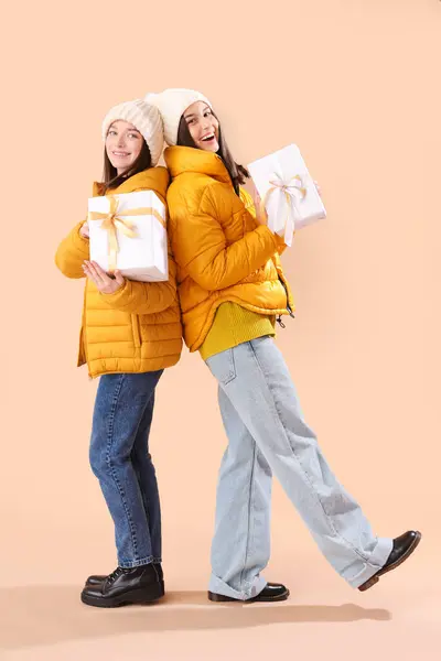 穿着冬季服装 背景为米黄色的圣诞礼物的年轻妇女 — 图库照片