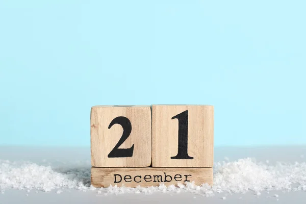 Cube calendar with date of winter solstice and snow on blue background