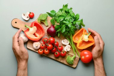 Ahşap tahtalı adam, taze sebzeler ve gri arka planda yeşillik.