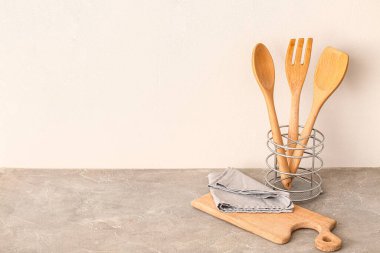 Mutfak gereçleri beyaz duvarın yanındaki gri masada.