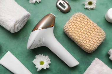 Kozmetik ürünleri, banyo malzemeleri ve grunge yeşil arka planda papatya çiçekleriyle modern fotoepilatör.